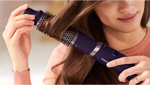 لقطة مقربة لامرأة تلف خصلة من شعرها حول الفرشاة الحرارية Philips 3000 Series BHA305 مقاس 38 مم للحصول على تموجات واسعة وحجم أكبر.