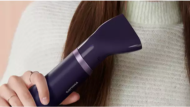 لقطة مقربة لعارضة تستخدم فوهة التركيز الضيقة في مصفف الشعر Philips BHA305 لتصفيف شعر خالٍ من التجعد ولامع.