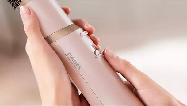لقطة مقربة ليد تضبط مفتاح التحكم في درجة الحرارة والسرعة على مقبض مصفف الشعر Philips BHA310 الوردي.